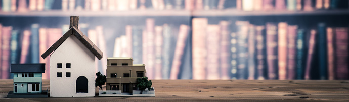 cardboard houses on a table with a bookshelf in the background